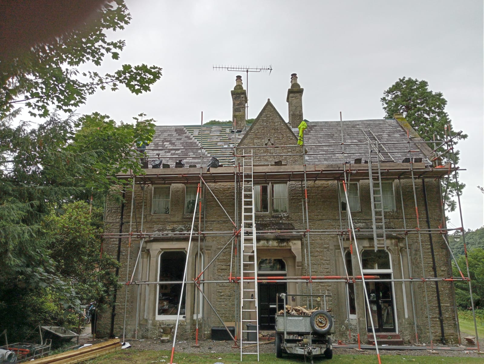 A large stone house with scaffold and ladders up to the roof